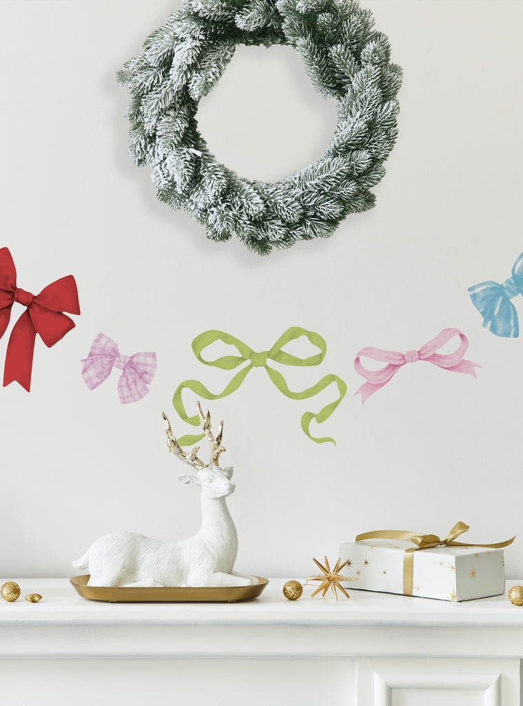 Colorful holiday ribbons stickers arranged on a wall above a white reindeer figurine and gift box with wreath decor