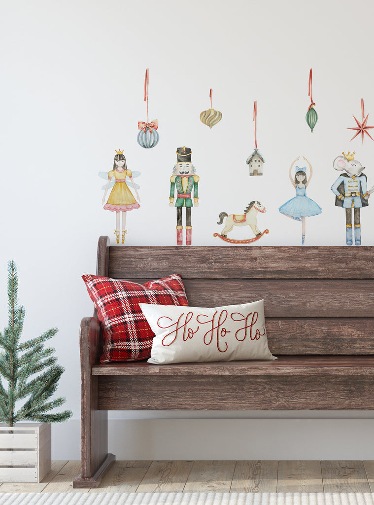 Cozy holiday scene with Nutcracker Ballet wall stickers above a wooden bench adorned with festive pillows and a small pine tree.