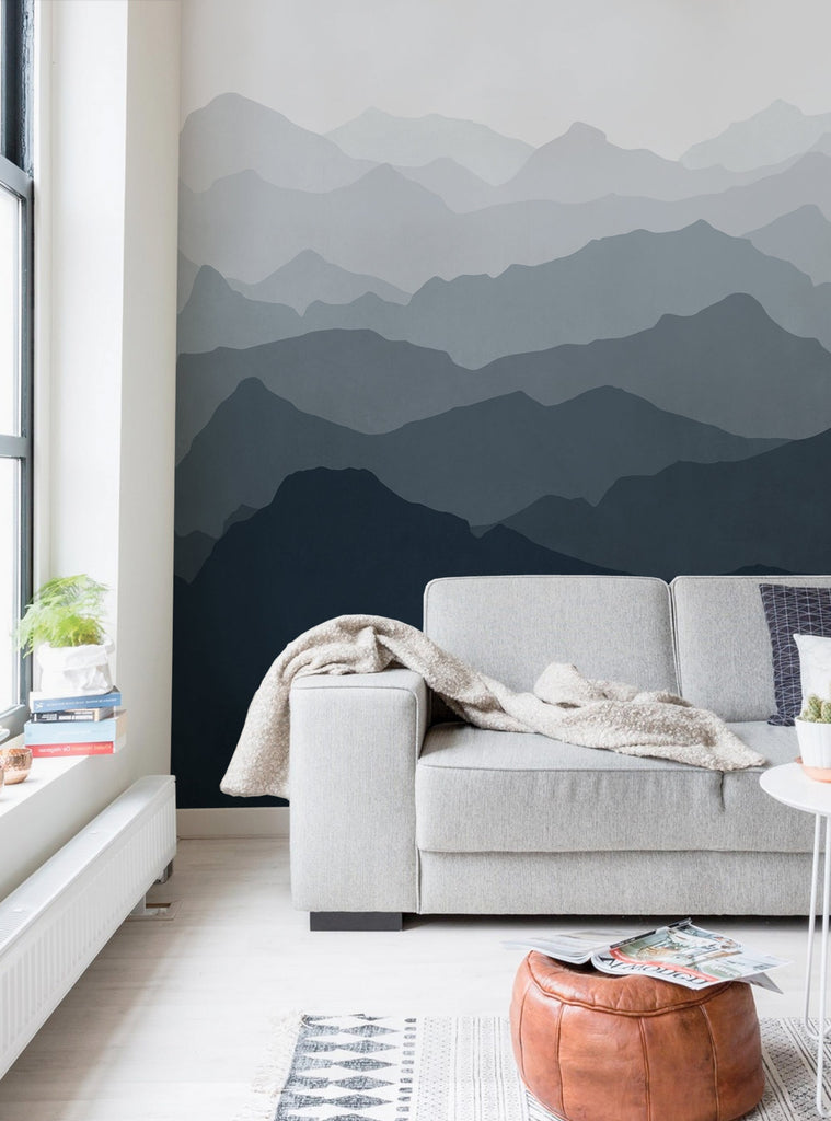 Serene mountain landscape mural with layers of misty mountain silhouettes in shades of grey, providing a captivating and visually striking backdrop for this cozy living space. Featured Collection, Top Sellers, Wall Murals, Peel and Stick Wallpaper, Nature Wallpaper, Kids and Baby Nursery Wallpaper, Nature Murals, Scenery Murals, Kids Murals, All Products, Wallpaper and Murals.