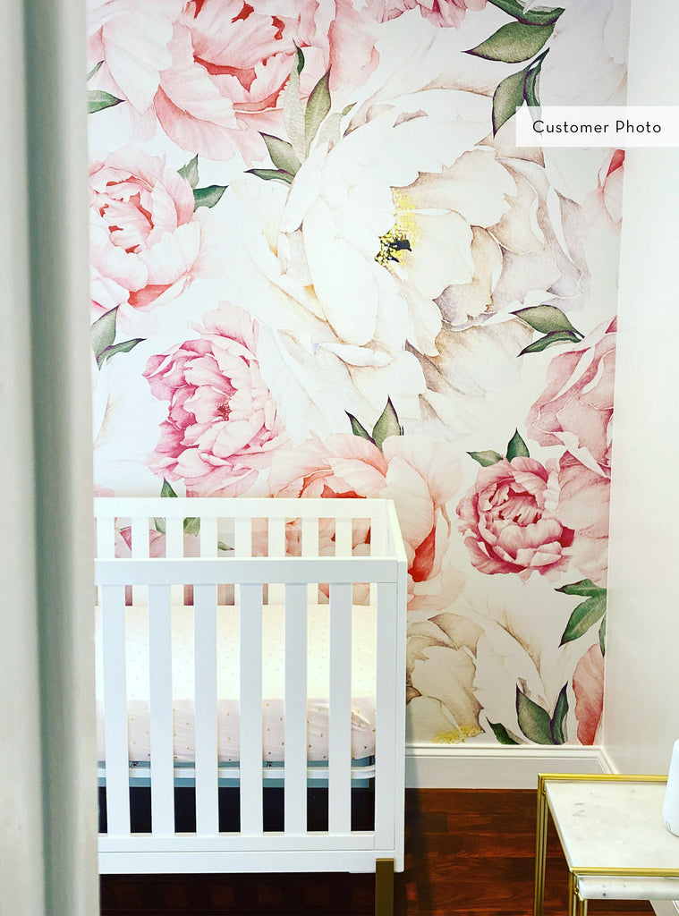 Girl’s nursery featuring soft pink and white peony flower mural wallpaper from the Floral Wallpaper collection with white crib and gold table