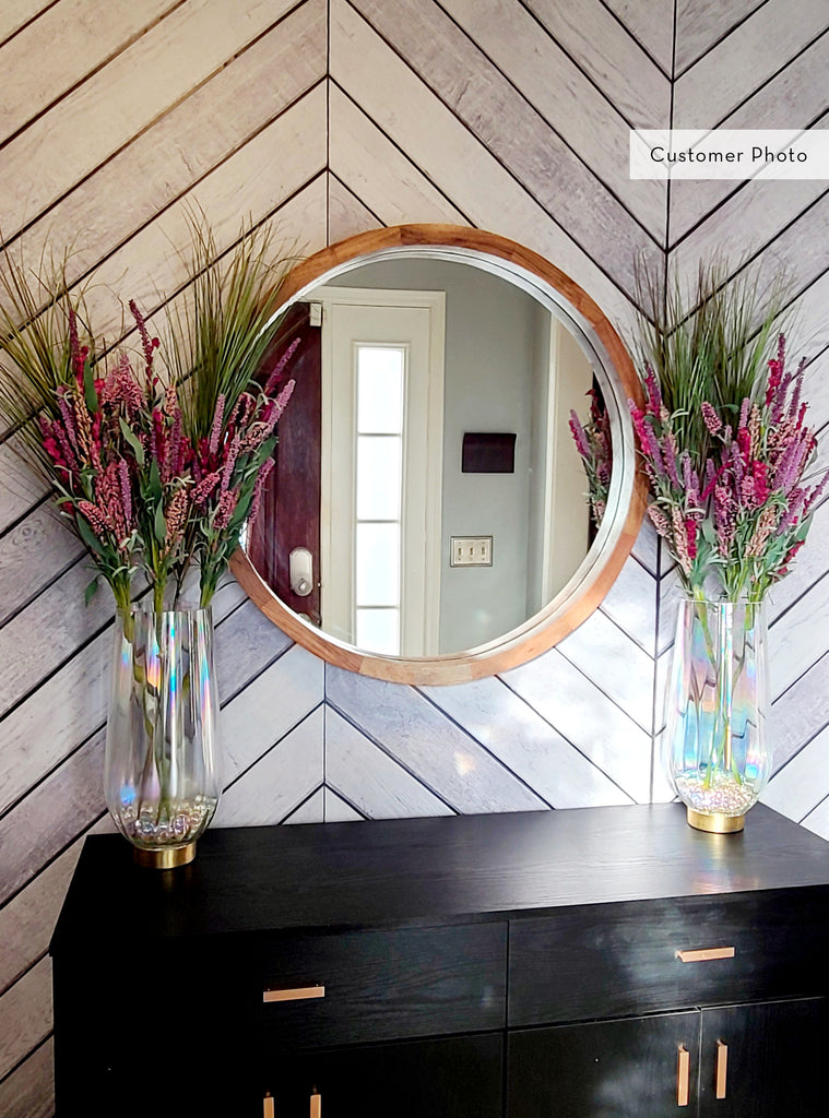 Chevron grey and white wood accent mural wallpaper with round mirror and decorative vases on black console in a stylish entryway setting