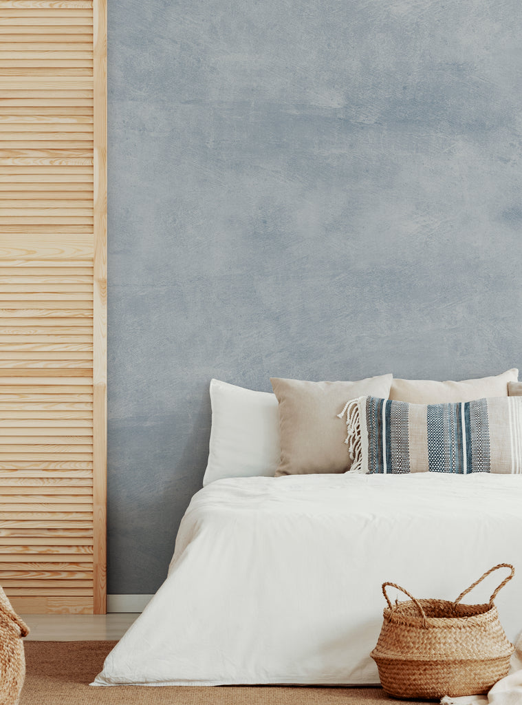 Modern bedroom with Venetian plaster faux texture wall mural in soft grey tone, featuring neutral bedding and woven baskets on beige rug
