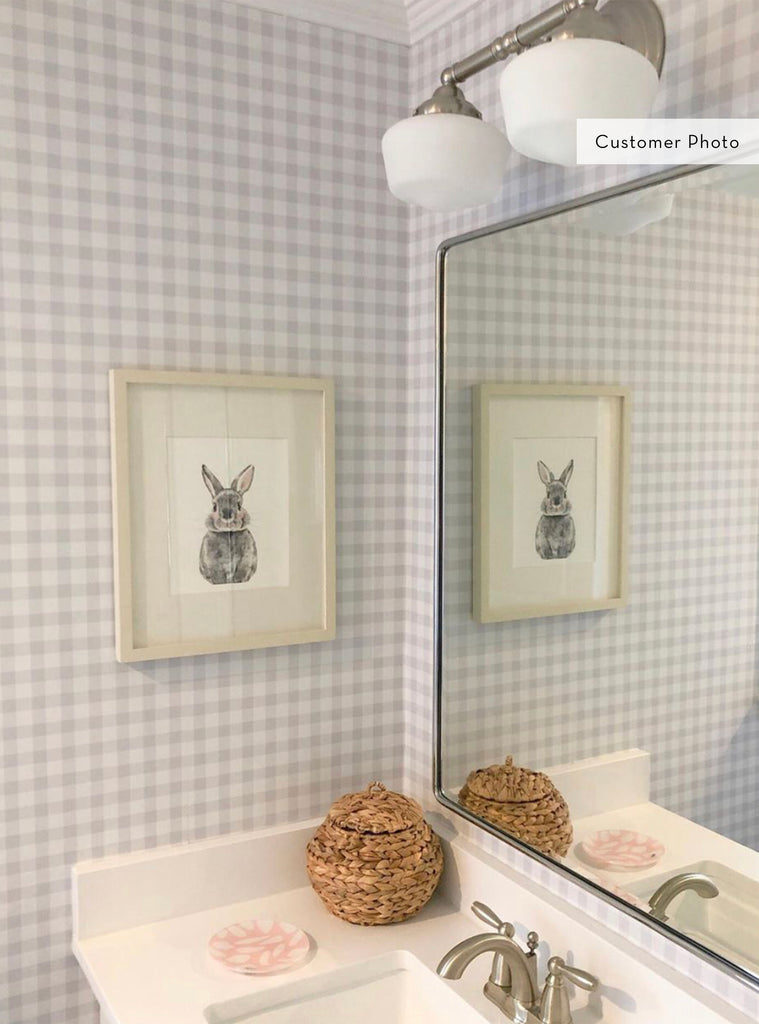 Modern farmhouse bathroom with soft grey gingham check wallpaper, wicker basket, framed bunny art, and clean white sink area with mirror.