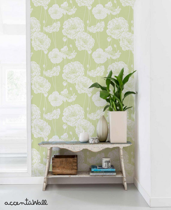 Light green wall with white detailed peony floral wallpaper in a modern room featuring a rustic table and green plant decor