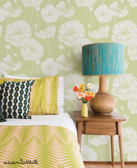 Bedroom with Peony Flowers Wallpaper in soft green tones, complemented by patterned pillows and wooden side table with lamp and flowers.