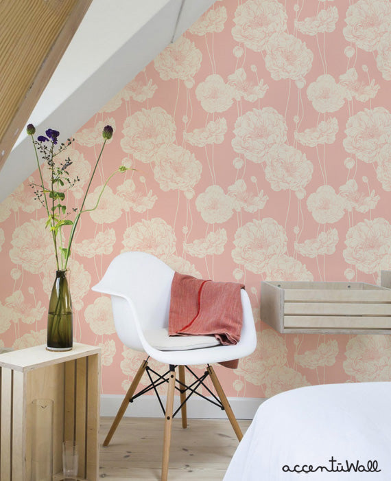Cozy corner with modern white chair and wooden accents against pink peony floral wallpaper in a bright, airy room setting