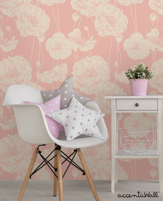 Cozy room featuring Peony Wallpaper in soft pink with large floral patterns, a white chair with star pillows, and a white side table with plant.
