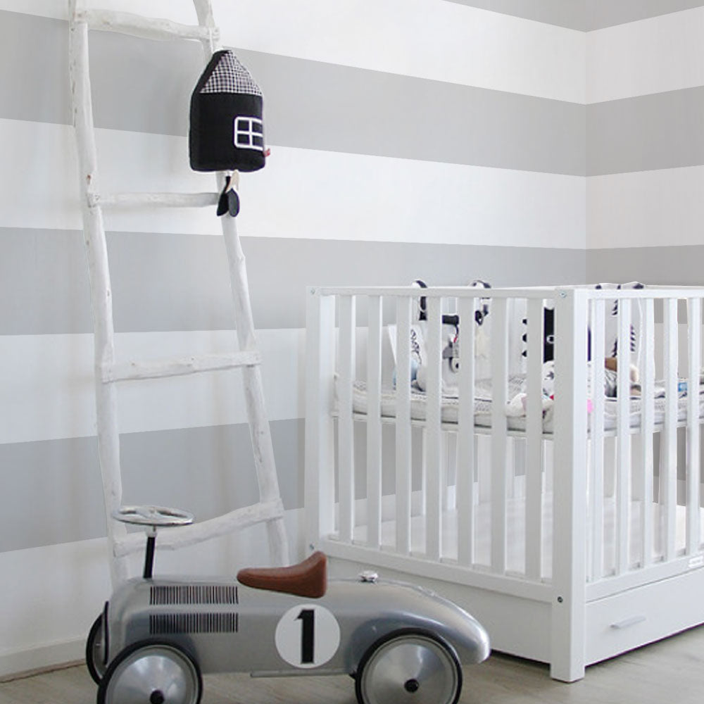 Bright nursery with Horizontal Stripe Bold wallpaper in soft gray and white paired with minimalist white crib and vintage toy car