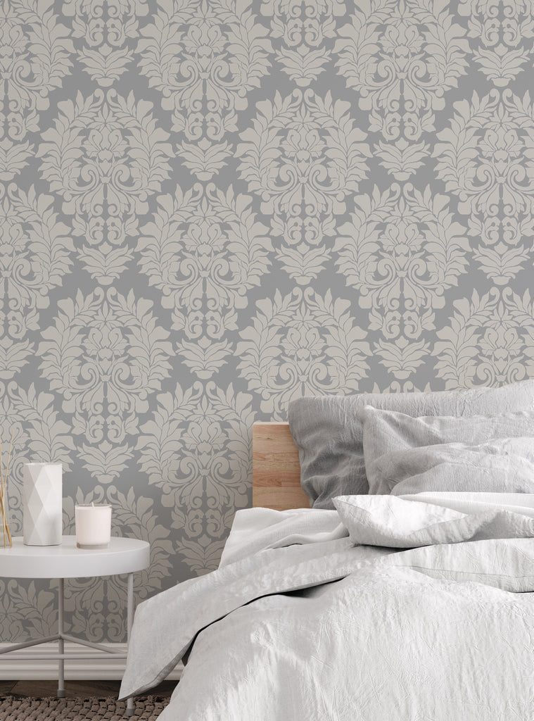 Elegant damask classic peel and stick wallpaper in grey and beige tones behind a cozy modern bedroom setup