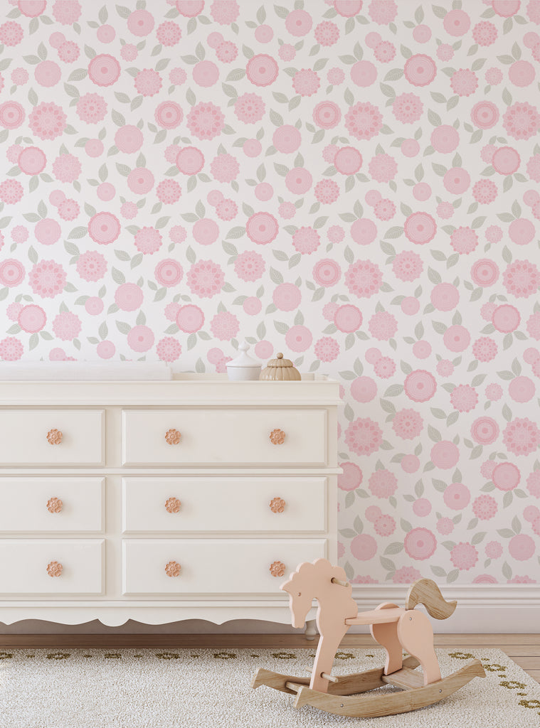 Light pink floral wallpaper with leafy patterns in a cozy nursery setting featuring a white dresser and wooden rocking horse