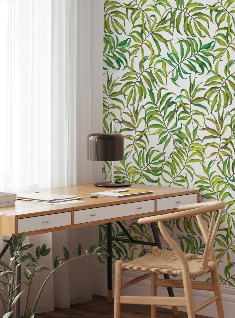 Home office space featuring Tropical Leaves wallpaper with vibrant green foliage and natural wood furniture in a bright setting