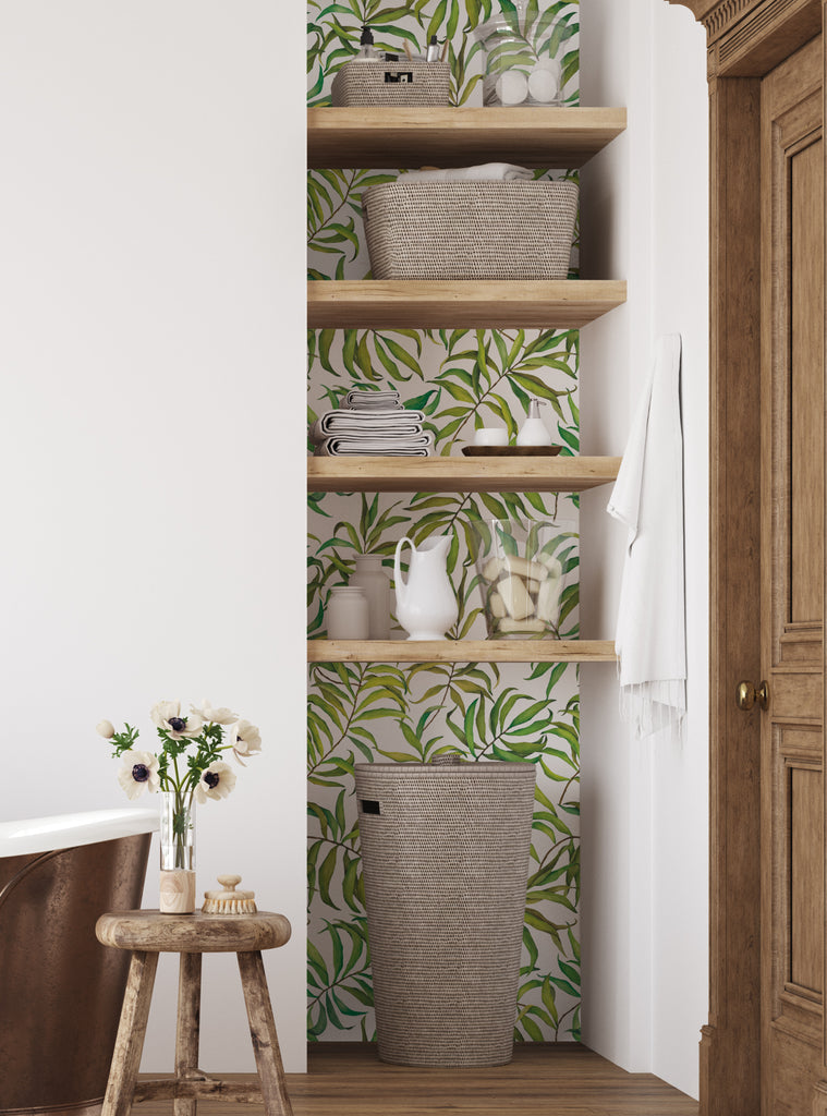 Bathroom corner with tropical leaves wallpaper behind wooden shelves holding baskets, towels, and decorative items in a cozy home setting