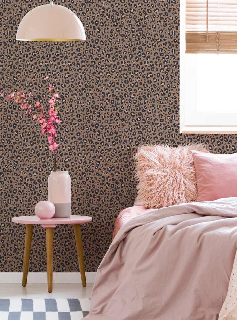 Cozy bedroom corner with animal print leopard wallpaper, soft pink bedding, textured pillows, and a small round side table with flowers