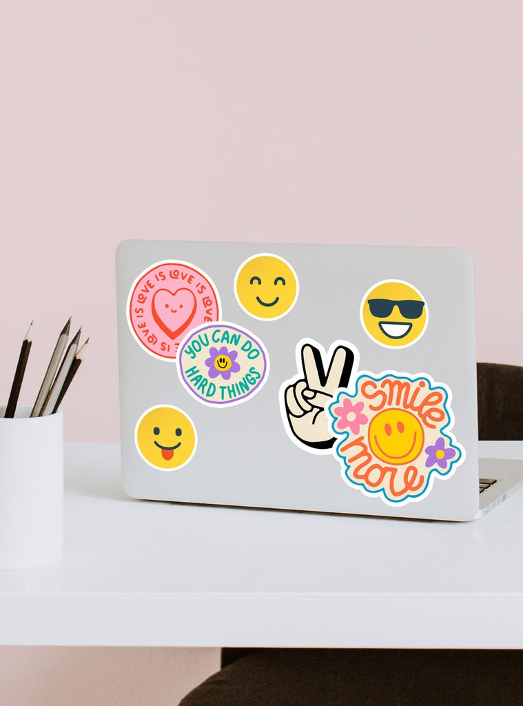 A laptop decorated with colorful emoji and motivational stickers expressing positivity and encouragement for back to school.