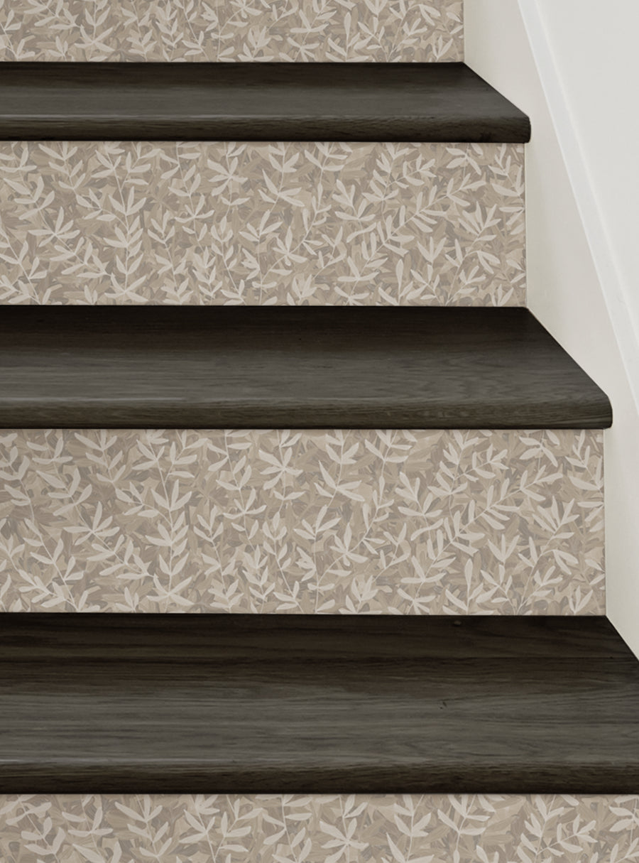 The image depicts a set of wooden stairs with a floral patterned wallpaper design on the riser panels. The stairs have a dark, rich wood tone that complements the light, delicate floral motif on the riser surfaces. This stair riser design would add a touch of natural, forest-inspired beauty to any home, creating a serene and inviting atmosphere for every step. , Top Sellers,Stair Riser Decals,All Products