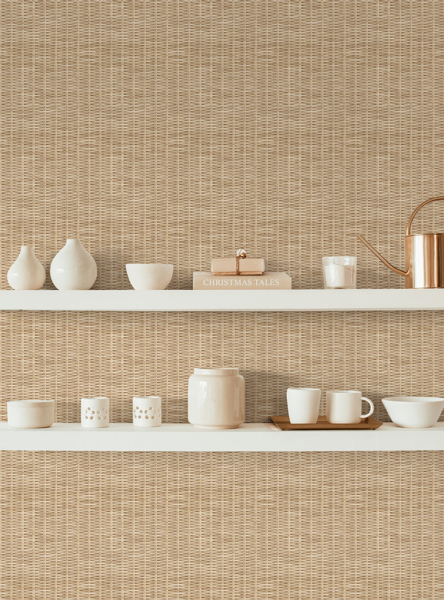 A beautifully arranged shelf displaying a variety of white ceramic and porcelain items against a backdrop of natural woven texture wallpaper in warm beige. The collection includes vases, bowls, mugs, and a decorative teapot, along with a book titled "Christmas Tales." The overall aesthetic is cozy and inviting, perfect for a stylish kitchen or dining area.