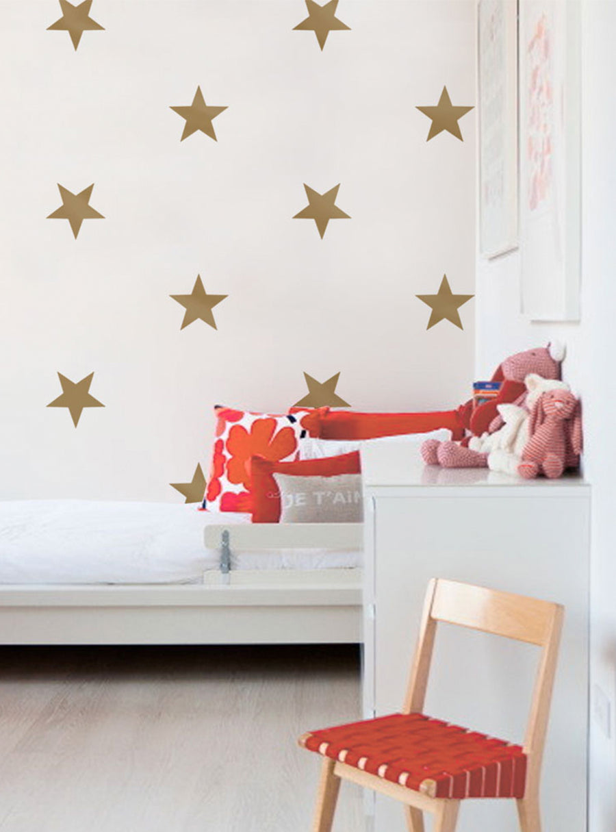 Large metallic gold stars adorn the bright white walls, creating a sparkling and whimsical atmosphere in this cozy children's space. The star decals add a touch of celestial wonder, perfect for decorating bedrooms, nurseries, and playrooms. This versatile wall art can easily be customized to match any color scheme. , Top Sellers,Wall Decals,Baby Nursery and Kids Wall Decals,All Products