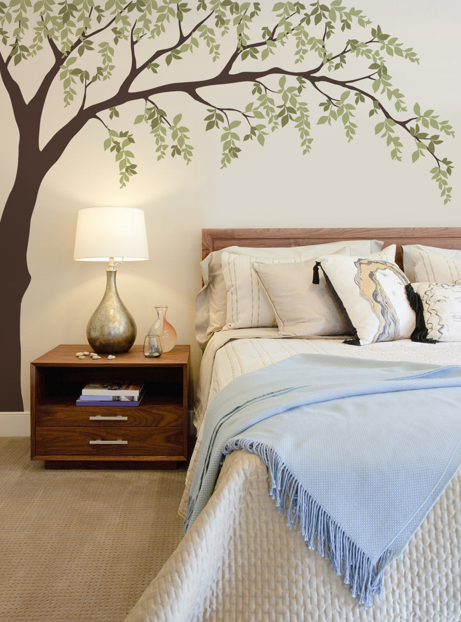 A large and lush tree branch with vibrant green leaves extending gracefully across the wall, creating a serene and natural ambiance in the cozy bedroom. , Top Sellers,Wall Decals,Floral Decals,Tree Decals,Baby Nursery and Kids Wall Decals,All Products