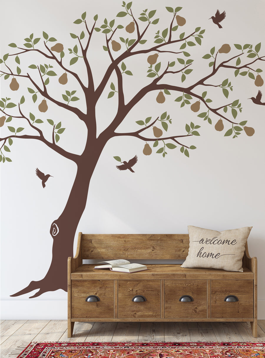 The image depicts a large pear tree wall decal adorned with flying hummingbirds. The tree's branches and leaves are rendered in shades of green, while the trunk and pears are in warm brown tones. The overall design has a natural, earthy aesthetic that would complement a variety of home decor styles. This wall decal would be an eye-catching focal point in any living room, nursery, or other space, making it a versatile addition to the Featured Coll