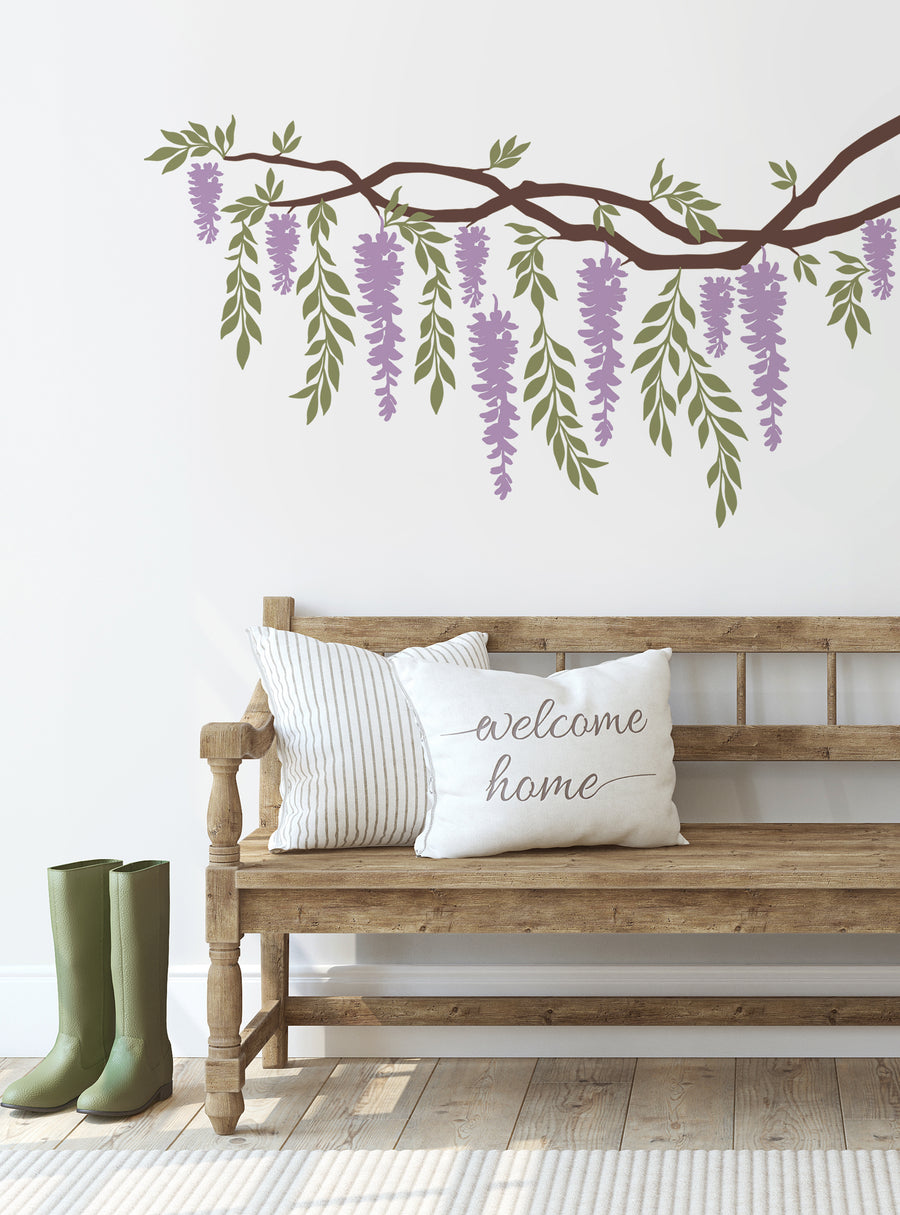 Wisteria Branch Vines Decal - Decorative floral wall art featuring cascading wisteria branches with lush green leaves and delicate purple blossoms, creating a serene and inviting ambiance. This versatile design complements various styles, from rustic to modern, and can be customized to suit your preferences. Top Sellers, Wall Decals, Baby Nursery and Kids Wall Decals, All Products, Dorm Room Ideas and Trends.