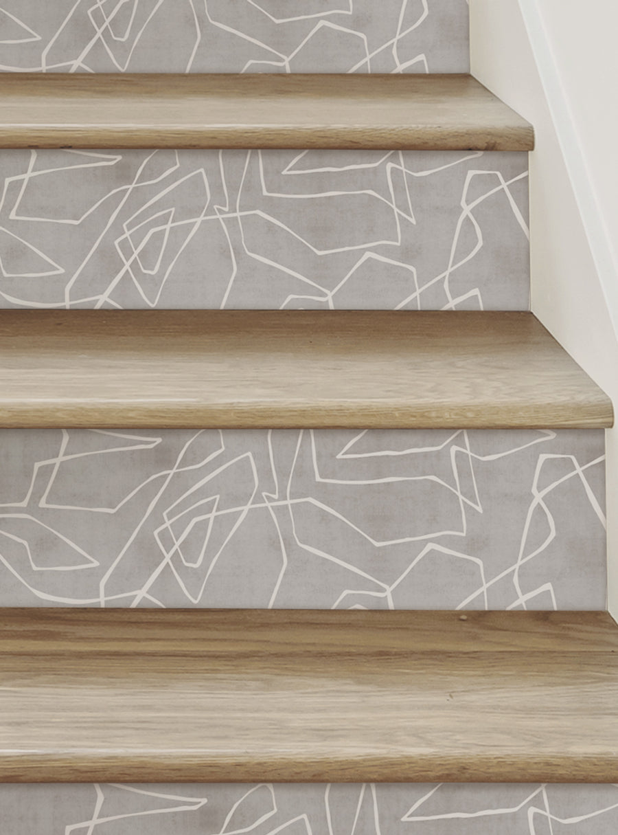 Captivating entangled lines in a textured, contemporary design adorn the stair risers, creating a dynamic and visually striking focal point. The geometric patterns add an elegant, modern touch, elevating the overall aesthetic and seamlessly blending with the natural wood tones. This versatile peel-and-stick solution allows for a mess-free, stress-free installation, making it an ideal choice for transforming stairs into a stylish and sophisticated