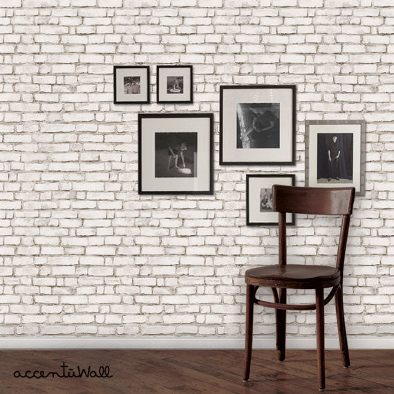 Decorative exposed brick wall with framed art displays and a wooden chair, showcasing the rustic and industrial style of this Shopify product - Brick Wallpaper. Featured Collection, Top Sellers, Peel and Stick Wallpaper, Surface & Texture Wallpaper, All Products, Unpasted Wallpaper, Wallpaper and Murals., W9073-White-Sample-Vinyl, W9073-White-Sample-Fabric, W9073-White-Sample-Unpasted