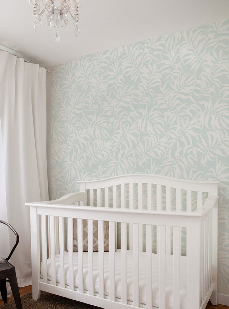Alt Text: Vibrant tropical palm leaves in soft pastel tones adorn the wallpaper, creating a lush and exotic backdrop for the cozy white crib in this inviting nursery space., Top Sellers,Peel and Stick Wallpaper,Floral Wallpaper,Nature Wallpaper,Kids and Baby Nursery Wallpaper,All Products,Unpasted Wallpaper,Wallpaper and Murals