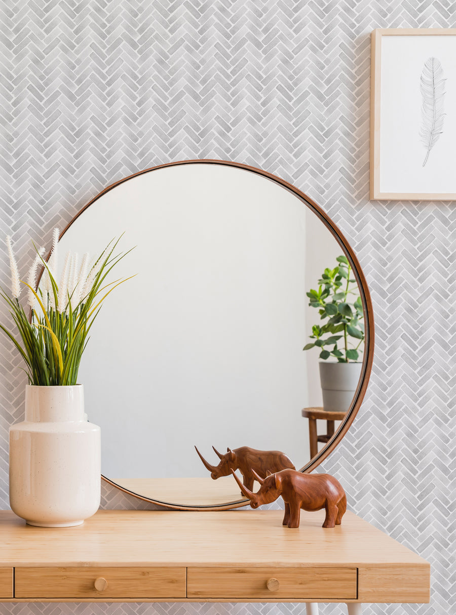 A stylish and visually appealing herringbone pattern wallpaper adorns the background, creating a warm and inviting atmosphere. The round mirror mounted on the wooden console table reflects the room, adding depth and dimension. Decorative elements like potted plants and wooden figurines complement the overall modern and minimalist aesthetic, making this a highly versatile and visually striking image. , Top Sellers,Peel and Stick Wallpaper,Geometri